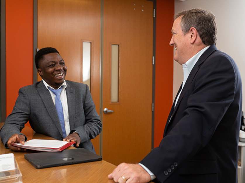 Two professional individuals talking and smiling in a large room