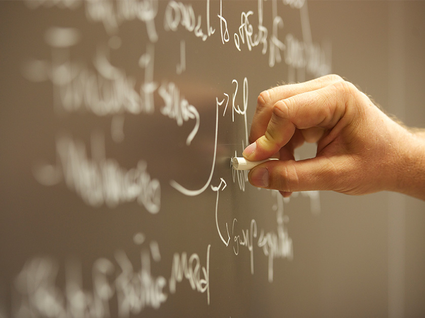 a professor writing an equation on a blackboard