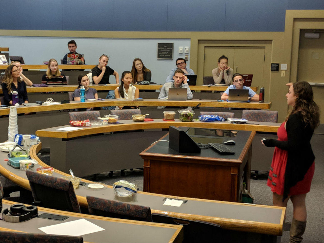 Student Alissa Geller, BSBA ’20, presents to Stacy Taubman, in the dark dress, center, front row.