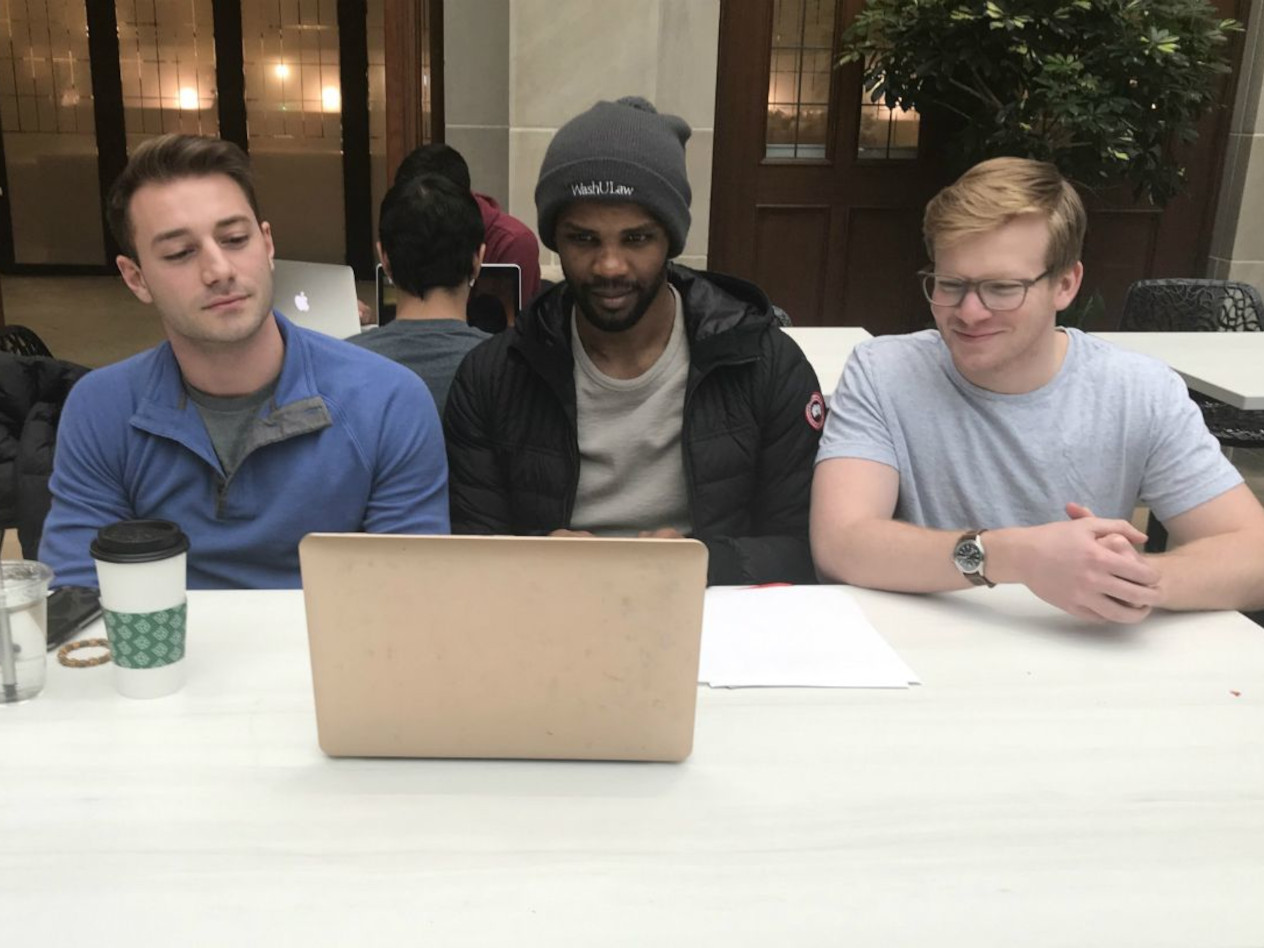 Three students socialize in front of a laptop screen