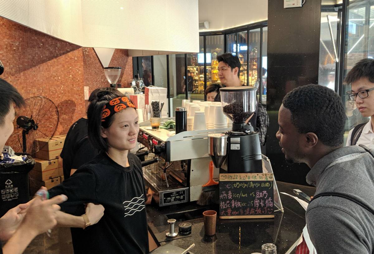 Duckenson Joseph, MBA 2021, questioning a store clerk at one of the Shanghai coffee shops he visited with his counterparts on team 10.