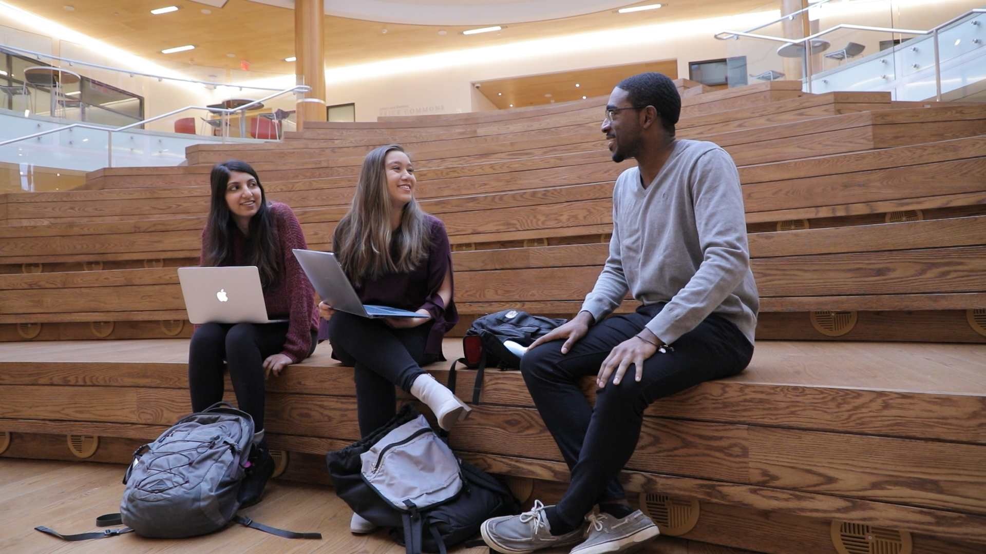 Three students socialize in Frick Auditorium