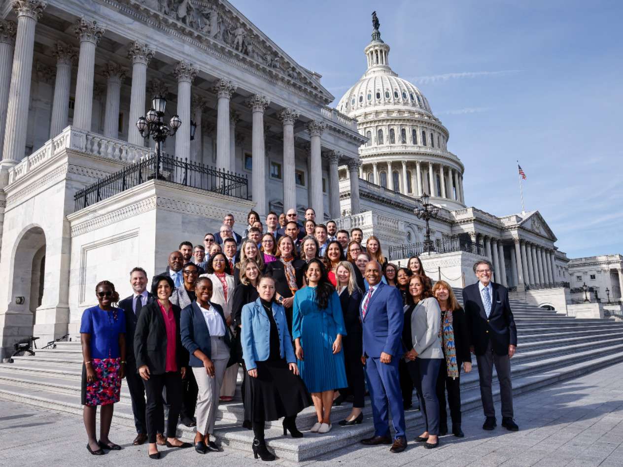 A group of men and women standing in front of US Capitol