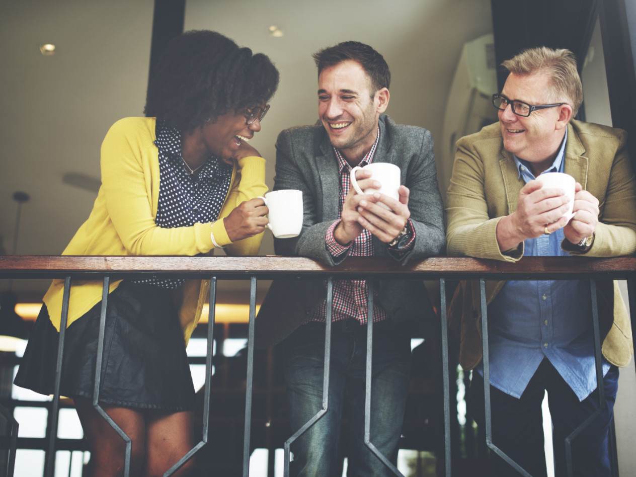 people holding coffee mugs and laughing together