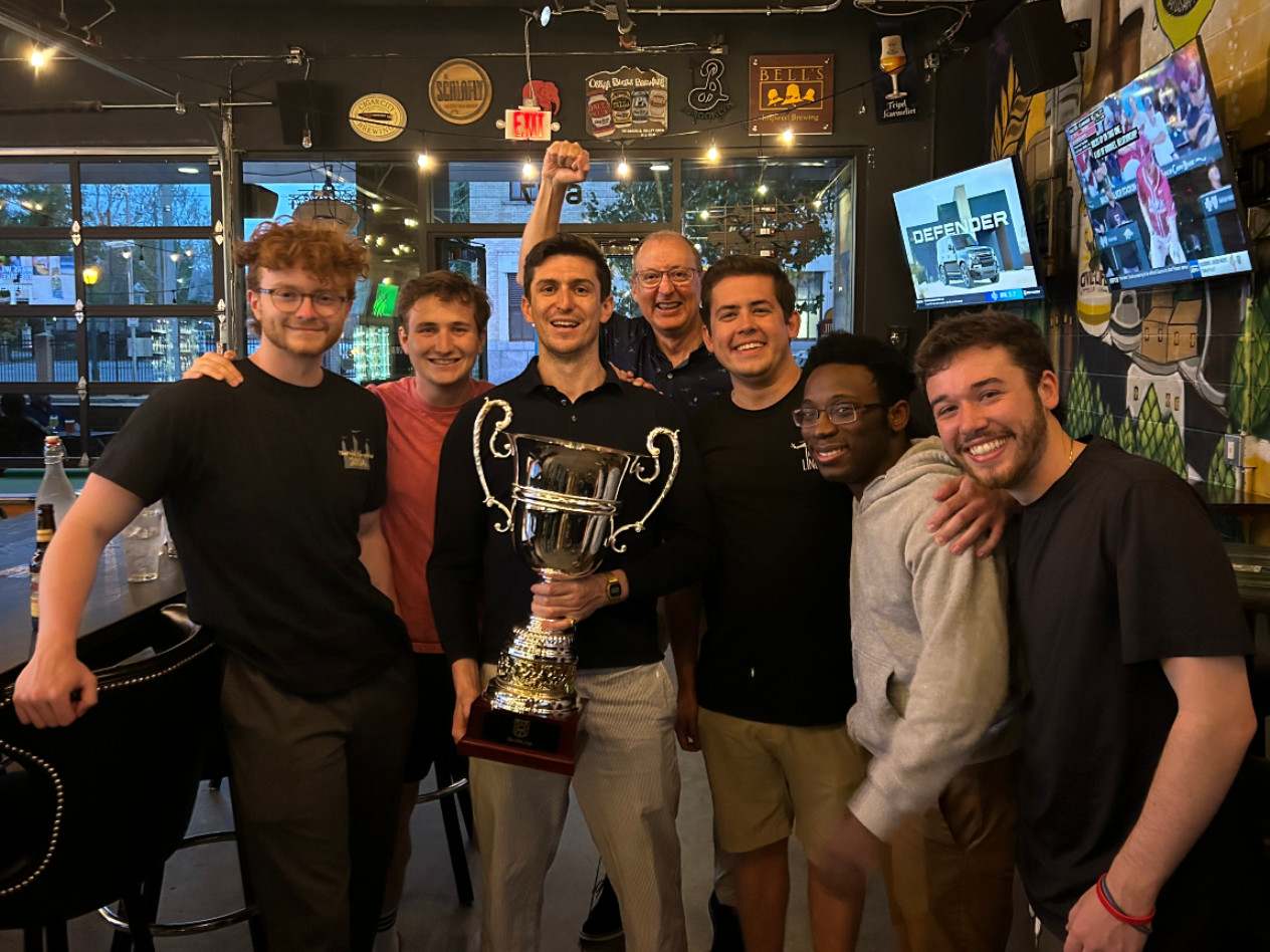 Group of men stands holding Olin Cuptrophy.