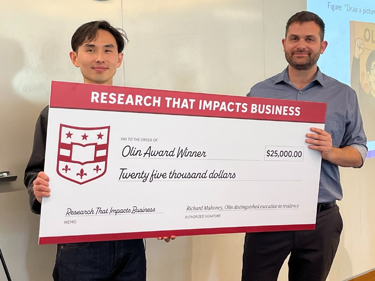 Two men hold an oversized check for $25,000