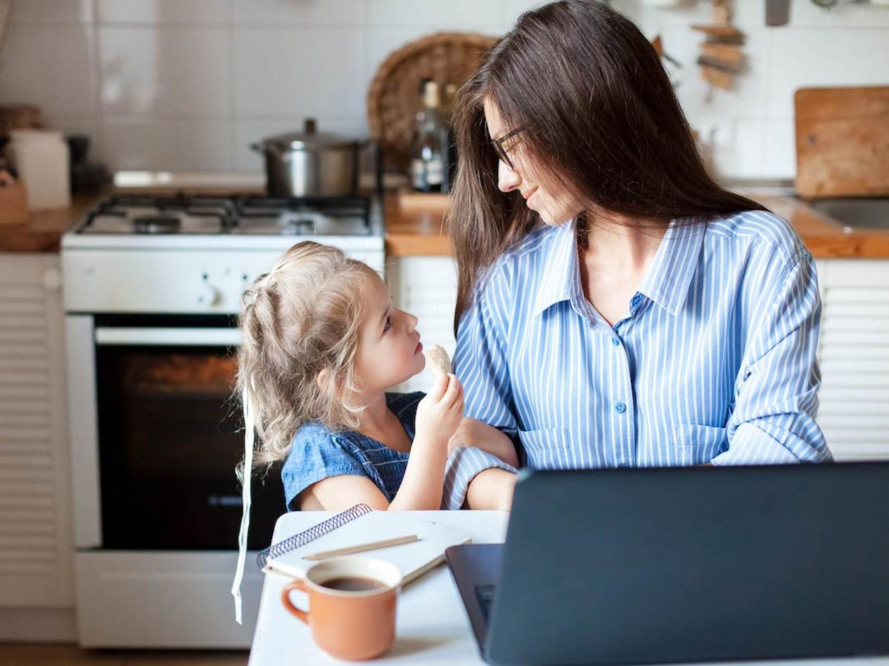 Mother working from home smiles at child