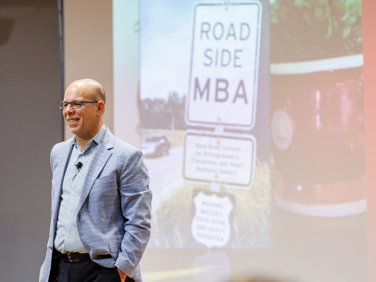 Olin Dean Mike Mazzeo stands in front of a projection with an image of his book "Roadside MBA"