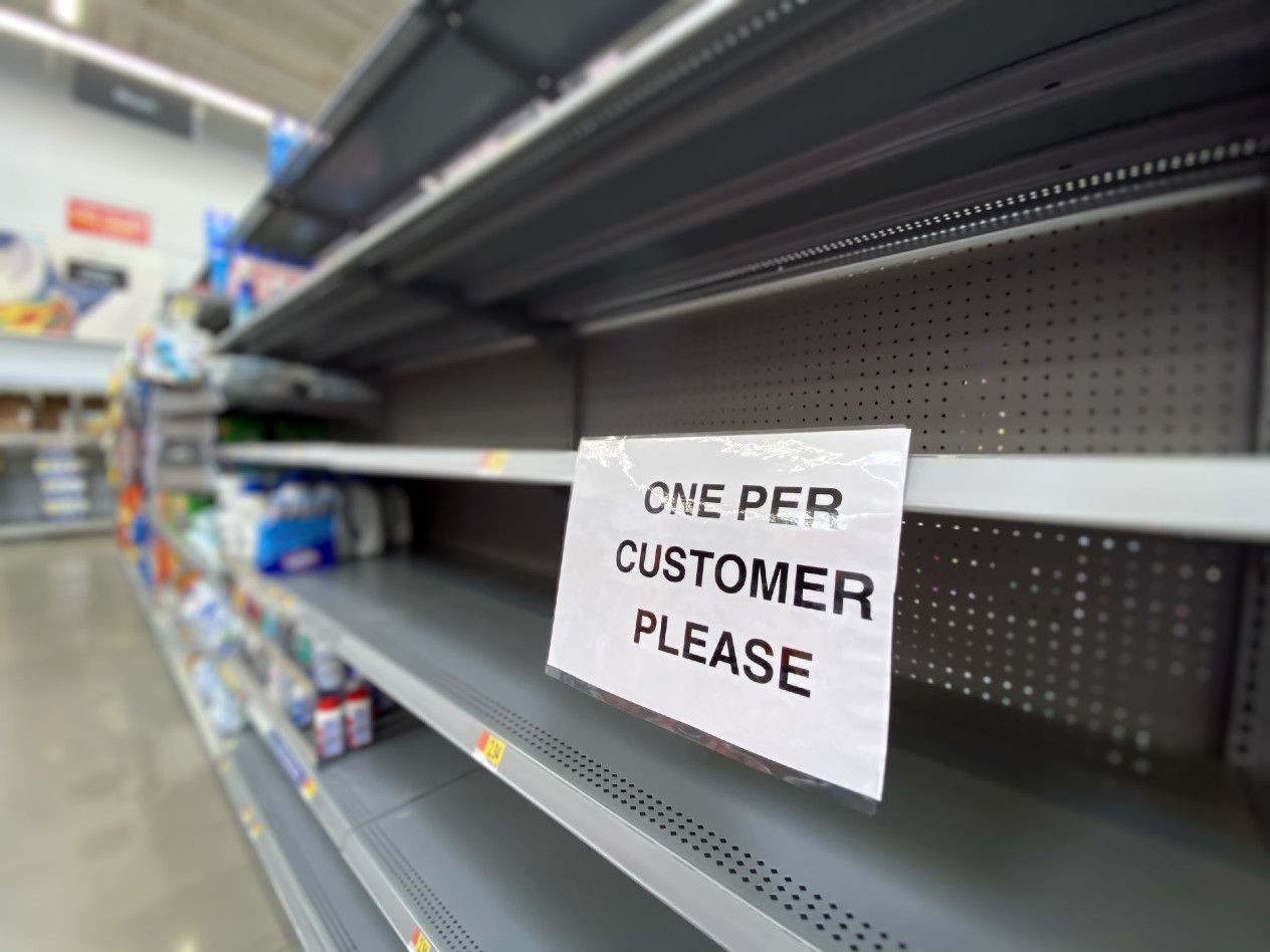 empty store shelves with a sign that reads "one per customer please"