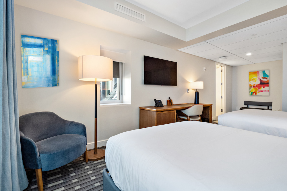 A hotel room with two beds, a desk and a side chair