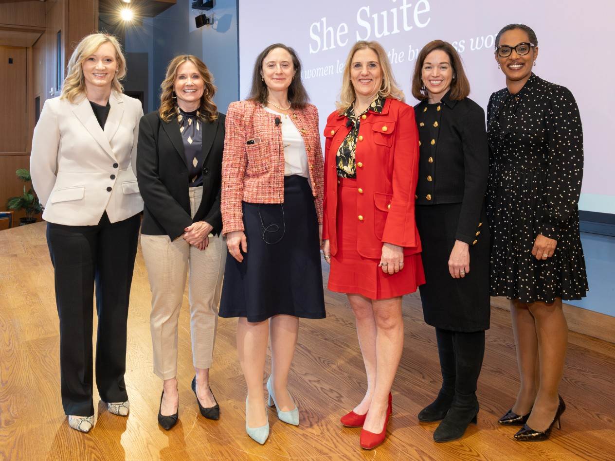 A group of six women stands on a stage