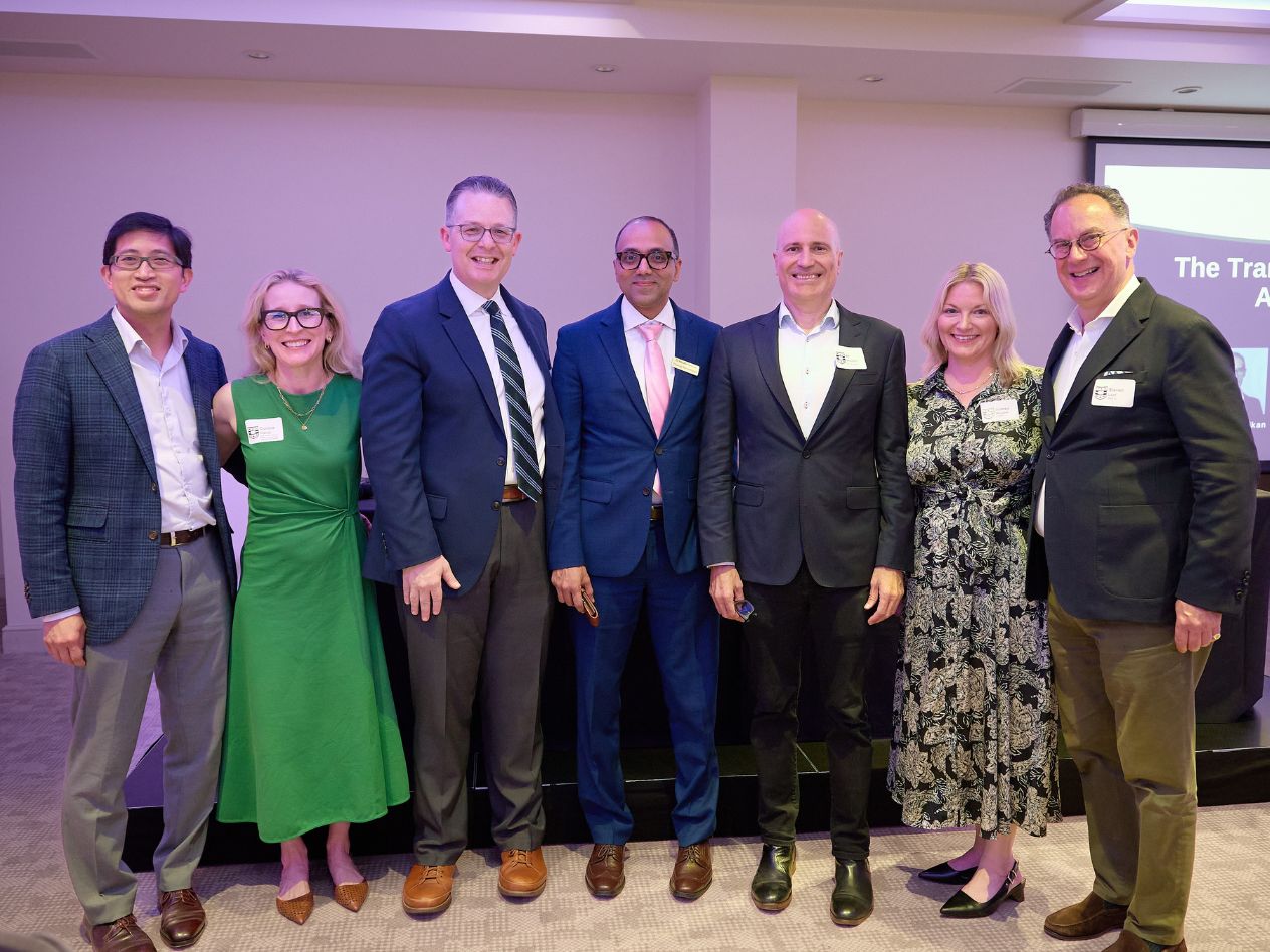 A group of seven men and women stand together, smiling. 