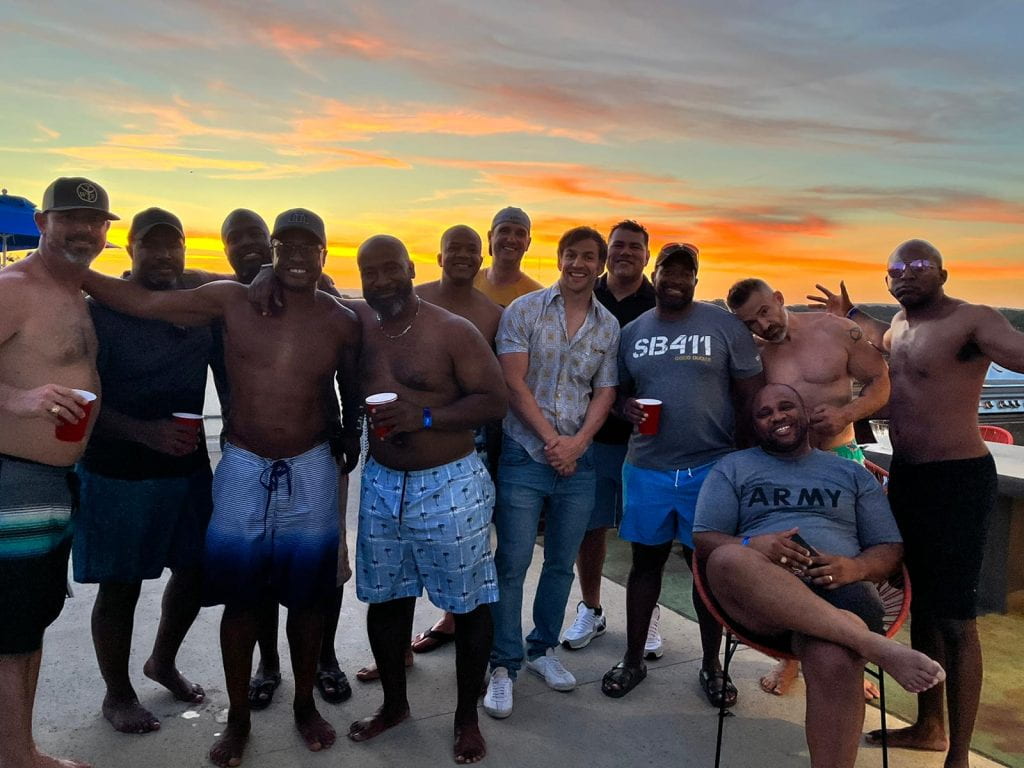 Group of men standing in front of a sunset