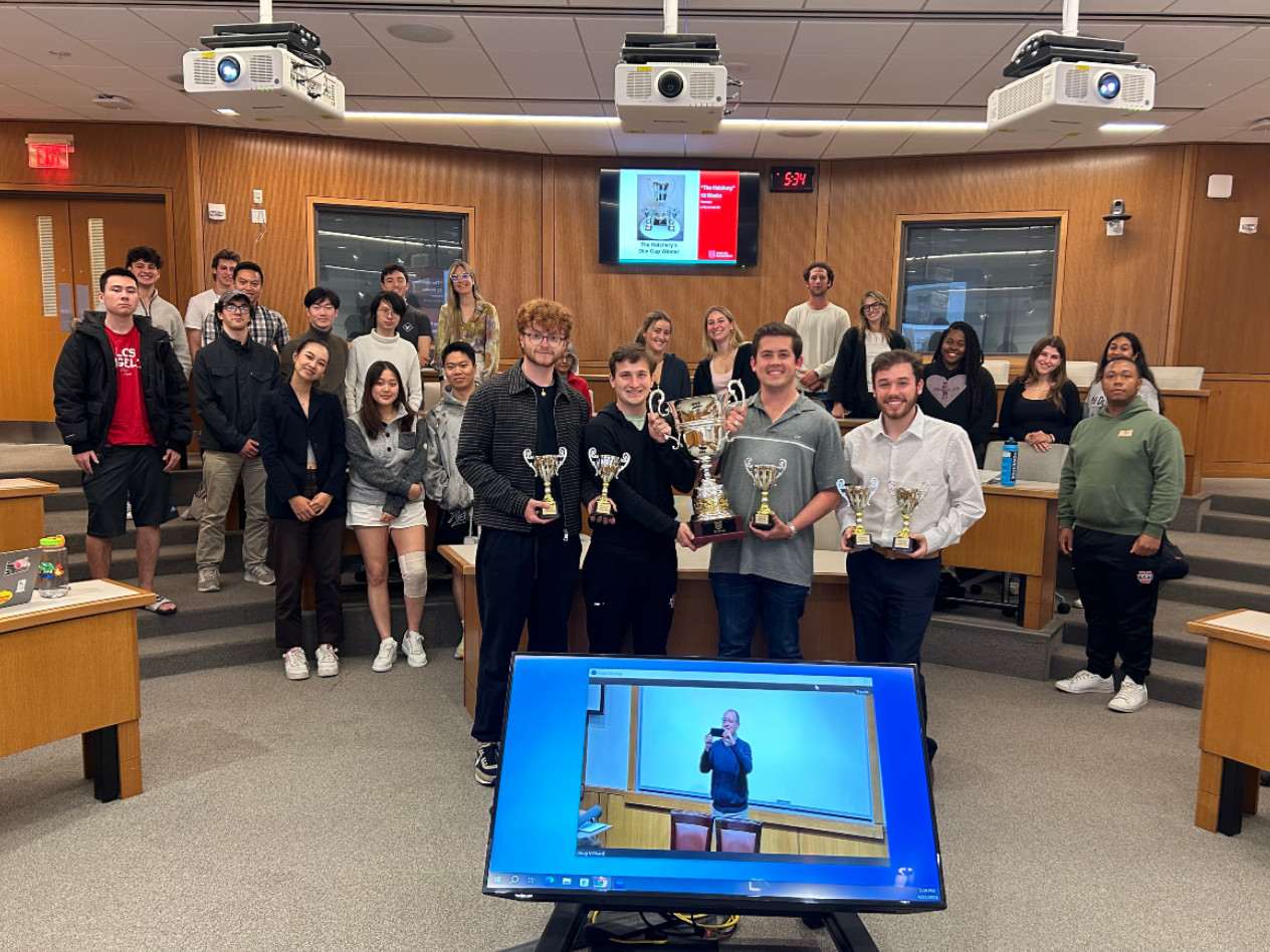 Students in a classroom, with four students holding trophies