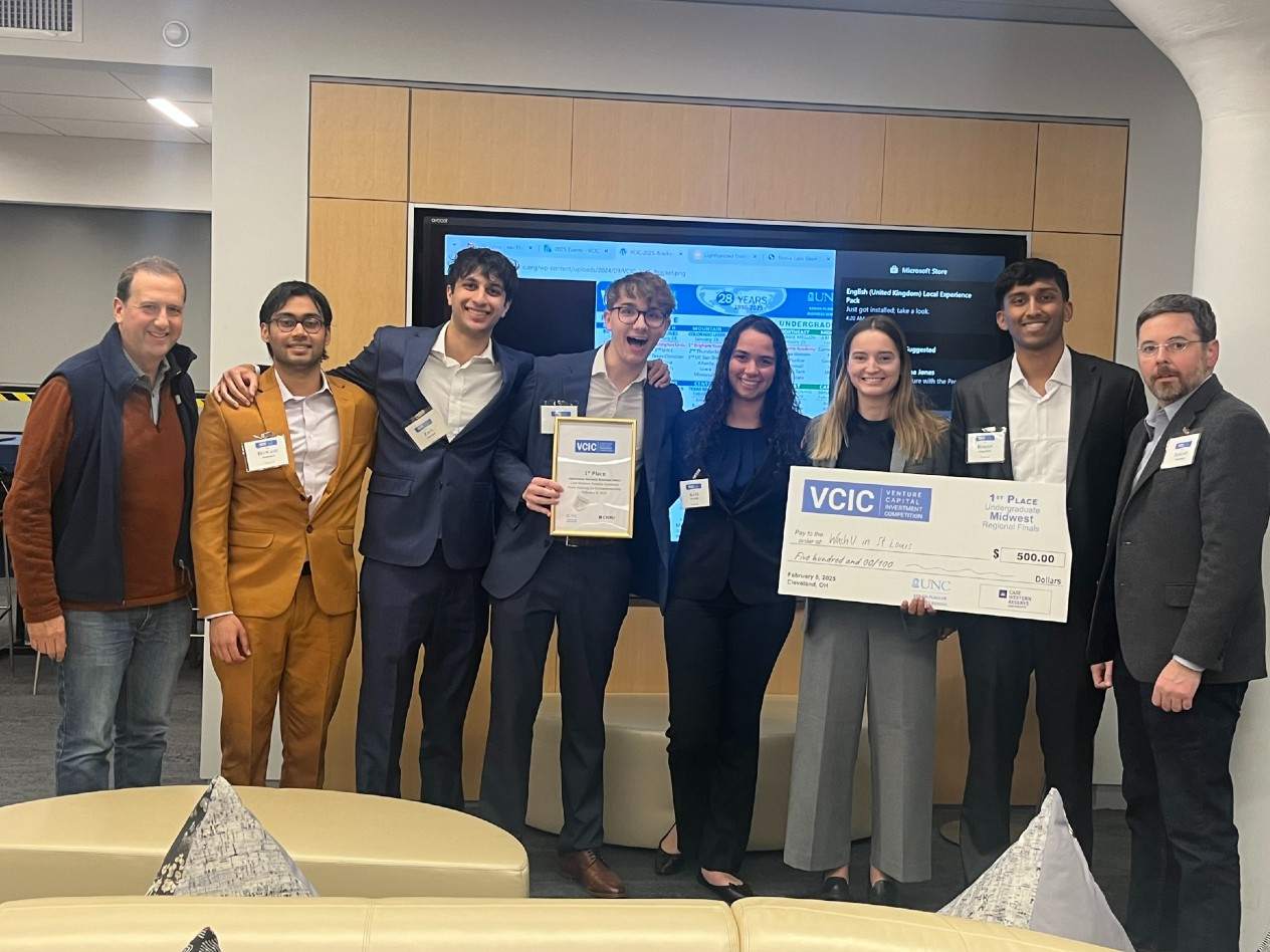 A group of six students and two advisors holds an oversized check.