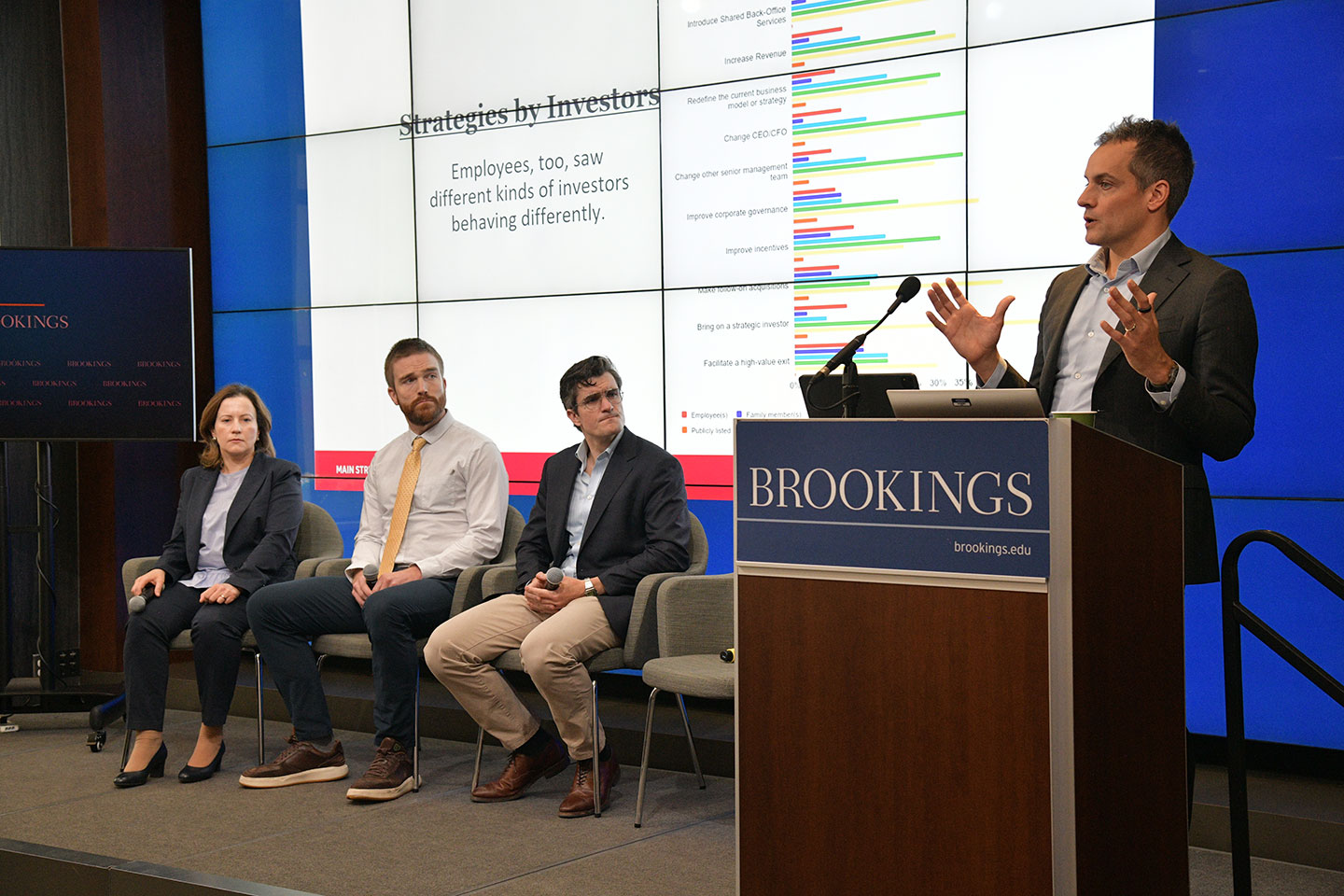 Peter Boumgarden speaking at a podium in front of a panel of guests on stage.